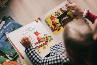 A child and adult reading an illustrated storybook together in a cozy setting.