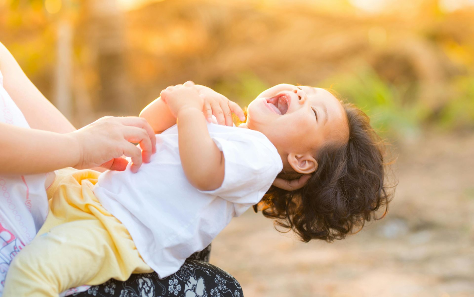 A happy baby enjoying playful moments outdoors, captured in warm summer lighting.