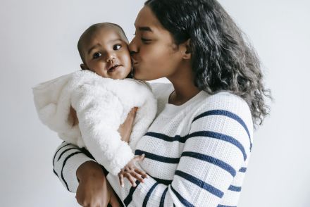 A beautiful moment of motherhood as a mother holds and kisses her baby.