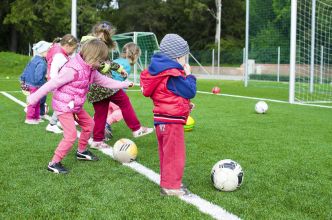 Kids having fun playing soccer outdoors on a sunny day in a park.